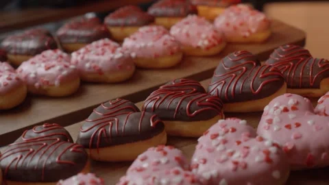 Heart-Shaped Donuts With Pink and Chocolate Icing Displayed on Bakery Wooden Stock Footage 334833652