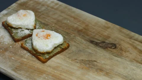 Heart-shaped eggs on toasts with smashed avocado and parmigiano cheese on a Stock Footage 150503384