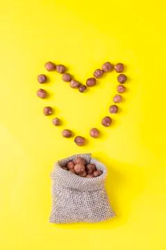 Heart shaped frame made of hazelnut on yellow paper, top view Stock Photos