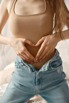 Heart-shaped gesture represents self-love and body positivity in casual hom.. Фото