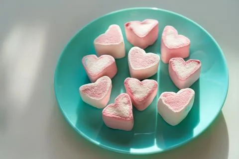 Heart shaped marshmallows lying on a blue turquoise plate 스톡 사진