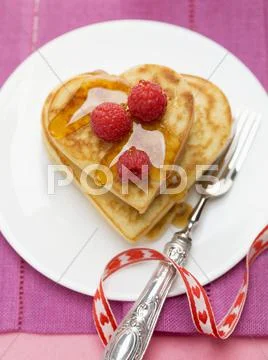 Heart-shaped pancakes with raspberries and maple syrup Stock-Fotos
