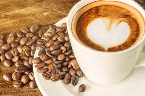 Heart-shaped pattern of coffee latte art, with coffee beans, valentine s d... Stock Photos