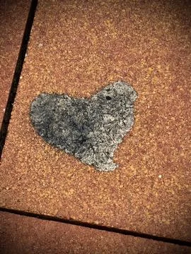 Heart-shaped pattern in damaged sidewalk paving. Stock Photos
