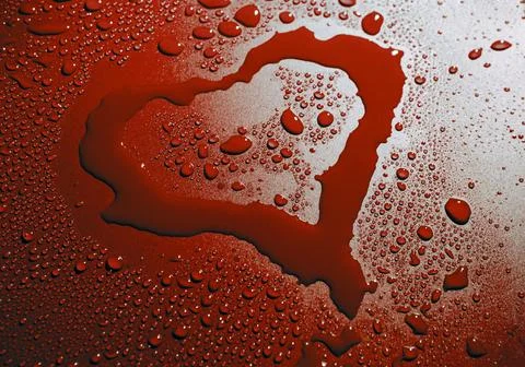 A heart shaped pattern on glass surface covered with droplets of water. Stock Photos