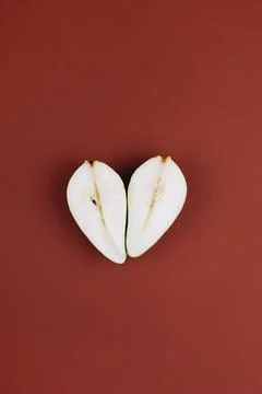 Heart shaped pear fall composition on dark burgundy background. Top view, flat Stock Photos