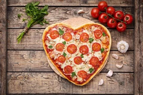 Heart shaped pizza margherita romantic love food concept with mozzarella Stock Photos