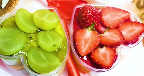 Heart shaped plastic dessert cups filled with syrupy strawberry slices and Video stock 311450910