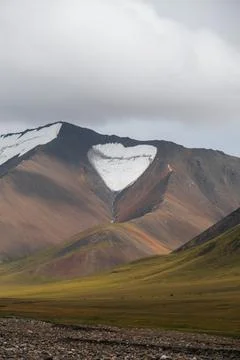 A heart-shaped snow patch on a mountain Stock Photos