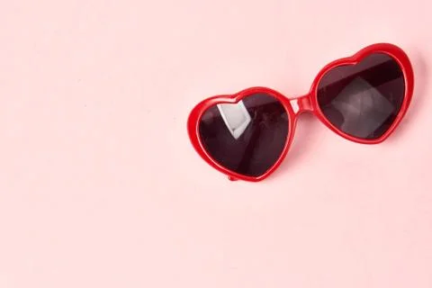 Heart shaped sunglasses with red frames on a pink background 스톡 사진