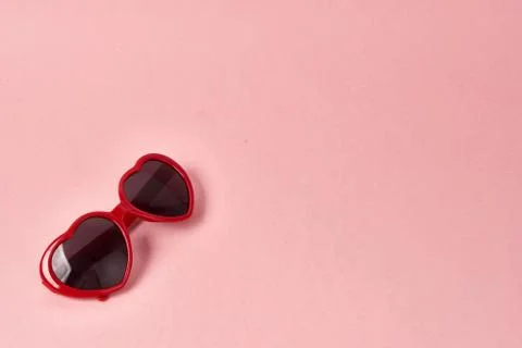 Heart shaped sunglasses with red frames on a pink background 스톡 사진