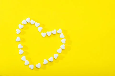 Heart-shaped tablets on a yellow background. Flat bed, top view. Stock Photos