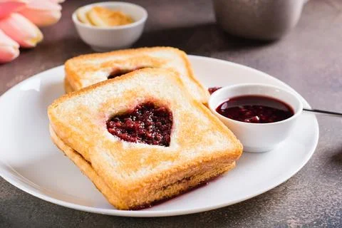 Heart shaped toast with raspberry jam on a plate. Food for lovers. Stock Photos