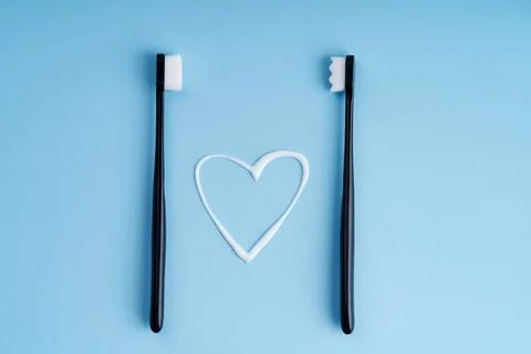 Heart shaped toothpaste between two toothbrushes close up Stock Photos