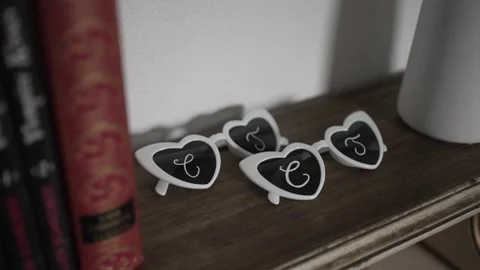 Heart shaped wedding sunglasses with initials on vintage bookshelf Video stock 311446474