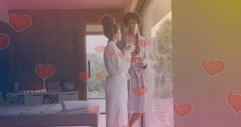 Heart shapes animation over two women in bathrobes talking near large window Video stock 304760406