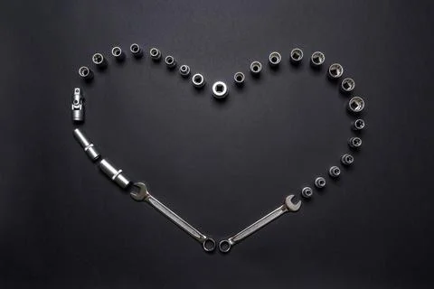 Heart symbol made of tool set on black background. Mechanic tools, wrenches o Stock Photos