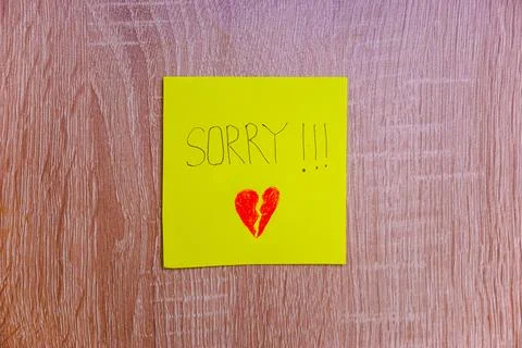 A heartfelt note on a yellow sticky note expresses deep remorse with a brok.. Stock Photos
