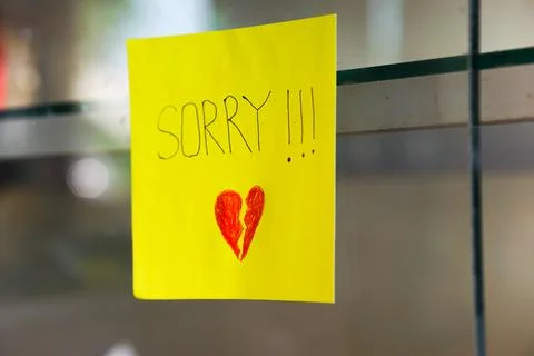 A heartfelt note on a yellow sticky note expresses deep remorse with a brok.. Stock Photos