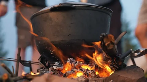 A hearth is burning, on which a cauldron of food is being cooked. Food on fire Stock Footage 272512409
