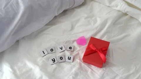Hearts flying on wedding bed with message love you and gift box, Valentine's day Stock Footage 168742744