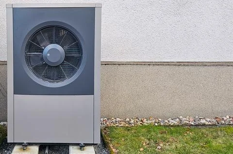 Heat pump unit installed outside building for energy efficient temperature .. Fotos de archivo