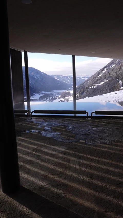 Heated indoor infinity pool facing snow filled Alpine valley and peaks Stock Footage 331987729