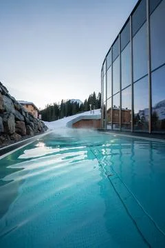 Heated infinity pool at glass walled spa in Oberlech, Austria at dusk Stock Photos