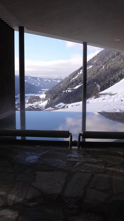 Heated infinity pool with pillars opens to Alpine valley and slopes Stock Footage 331987714