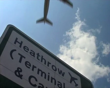 Heathrow sign with Plane Overhead CLOSE, London England GFSD Stock Footage