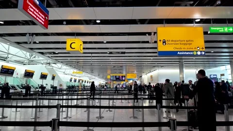 Heathrow Terminal 4 check-in hall with stanchion-lined queues, passengers Stock Footage 334973525
