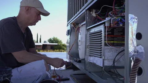 A heating and air technician servicing a rooftop HVAC unit Stock Footage 210234355