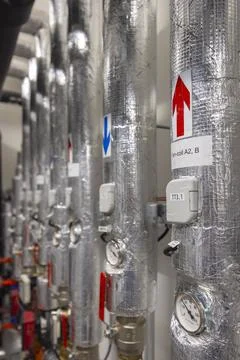 Heating and cooling system pipes running along wall in boiler room Foto stock