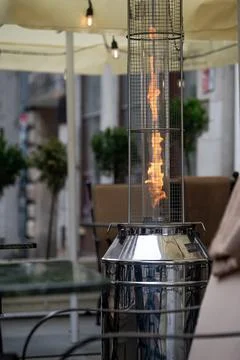 Heating device with flame in outdoor dining area during evening hours Stock Photos