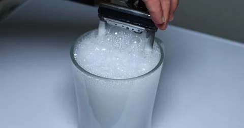 The heating element with limescale is immersed in a bubbling solution to remove Stockbeeldmateriaal 254189165