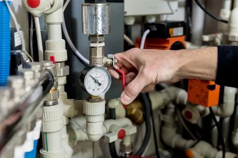 Heating engineer fixing modern heating system in boiler room. Stock Photos