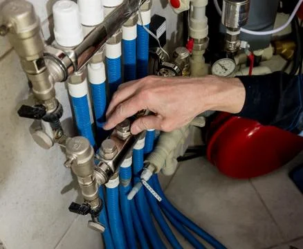 Heating engineer fixing modern heating system in boiler room. Stock Photos