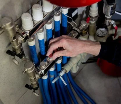 Heating engineer fixing modern heating system in boiler room. Stock Photos
