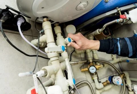 Heating engineer fixing modern heating system in boiler room. Stock Photos