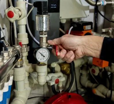 Heating engineer fixing modern heating system in boiler room. Stock Photos