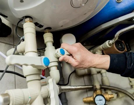 Heating engineer fixing modern heating system in boiler room. Stock Photos