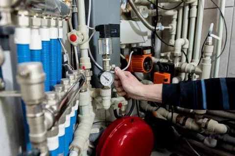 Heating engineer fixing modern heating system in boiler room. Stock Photos