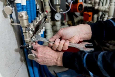 Heating engineer installing modern heating system in boiler room. Stock Photos