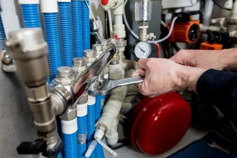 Heating engineer installing modern heating system in boiler room. Stock Photos