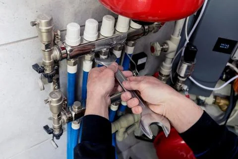 Heating engineer installing modern heating system in boiler room. Stock Photos