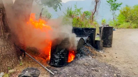 Heating up with fire taarcoal for raod constrction in hill station Stock Footage 279800152