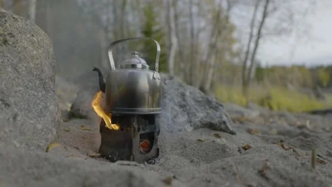 Heating up a kettle over open fire on happy stove Stock Footage 141846686