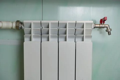 The heating radiator hangs on the wall. Stock Photos