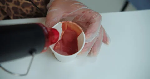Heating red cosmetic mixture in paper cup with heat gun Stock Footage 314597318