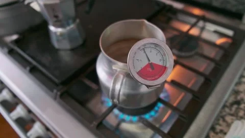 Heating something with thermometer on stove view and moka pot Stock Footage 169598598